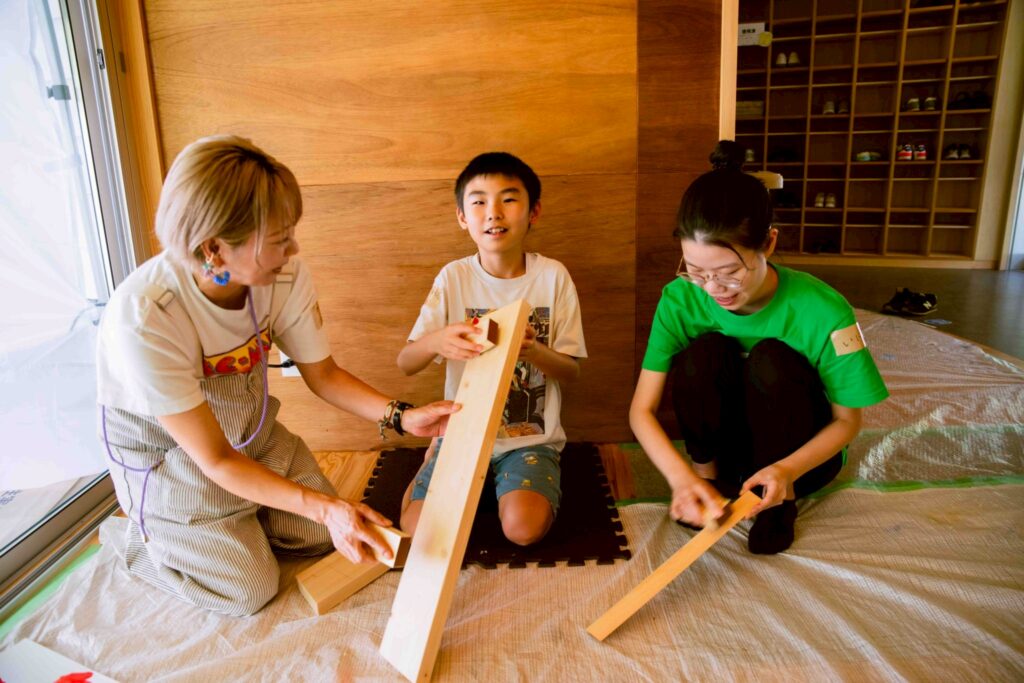 ニモカカのスタッフと保護者の間で木にヤスリをかけている画像