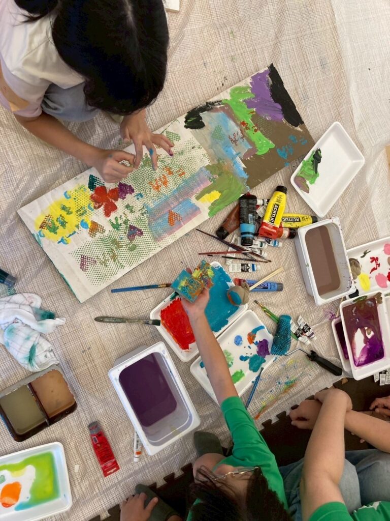 ワークショップで作成しているベンチの天板に絵を描く子供たちを上から撮影