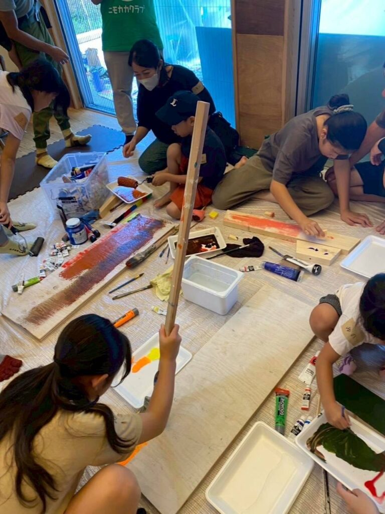 ワークショップ中にベンチになる木に絵の具で模様を描いている風景