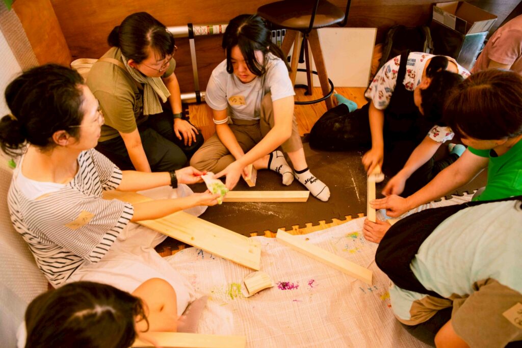 ニモカカのスタッフと子供たちが木にヤスリをかけている画像