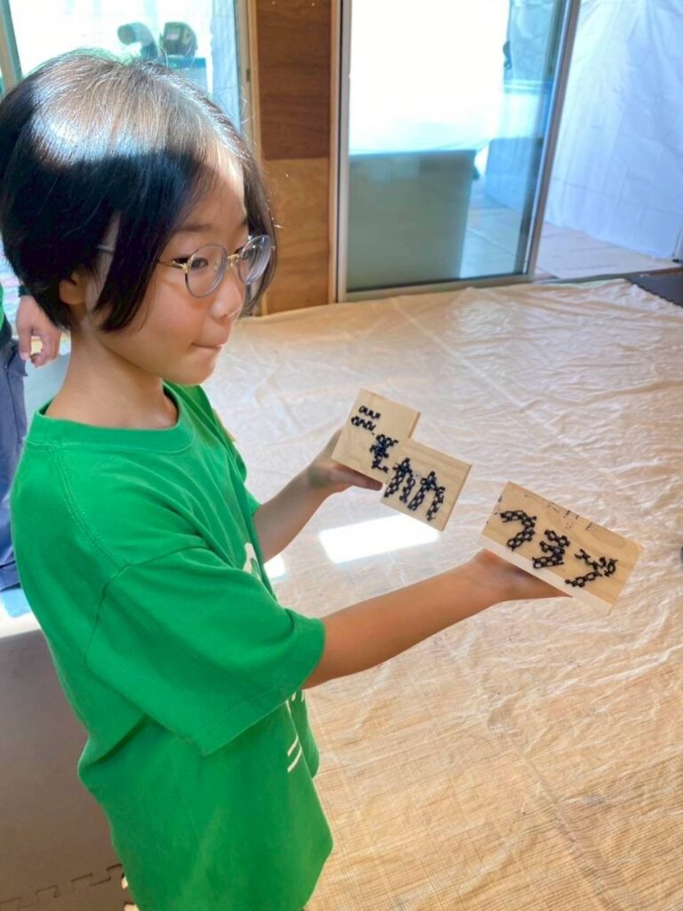 作ったベンチの端材でニモカカの看板を作って見せてくれている子供の写真