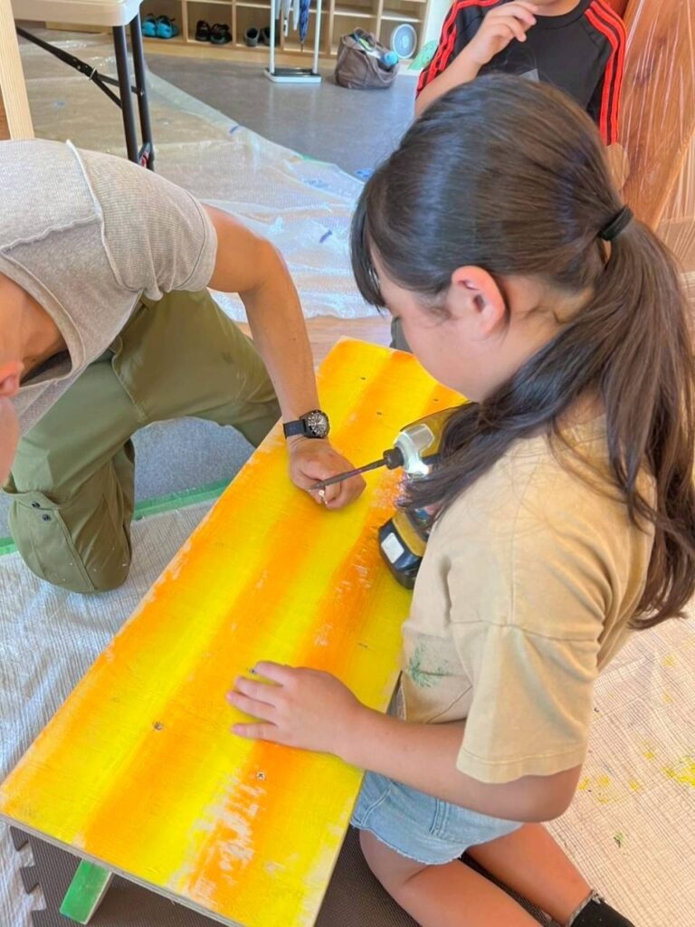 大人と一緒にドライバーを使ってネジ止めしている子供の写真